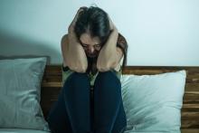 Indoors bed portrait of young desperate and depressed woman feeling scared and overwhelmed crying alone during COVID-19 virus home lockdown and quarantine